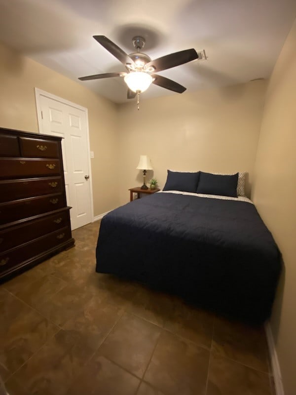 bedroom with ceiling fan and dark tile patterned floors