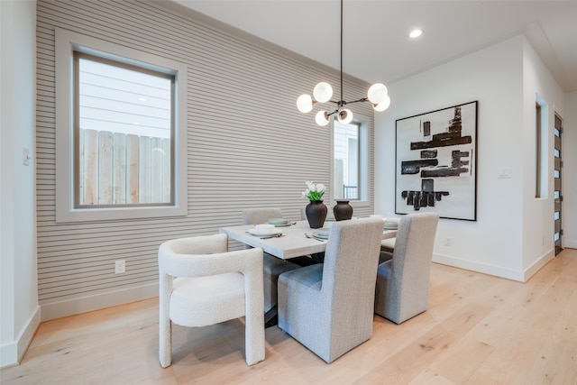 dining area with baseboards, light wood finished floors, and a chandelier