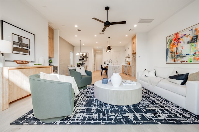 living room with ceiling fan with notable chandelier, recessed lighting, and visible vents