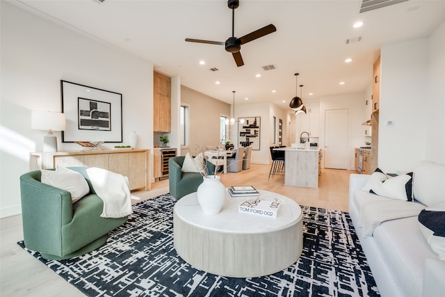 living area with recessed lighting, visible vents, wine cooler, and light wood-style floors