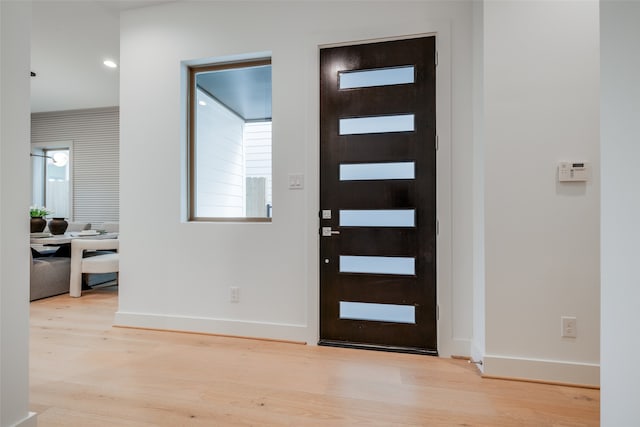 foyer with light wood-style flooring and baseboards