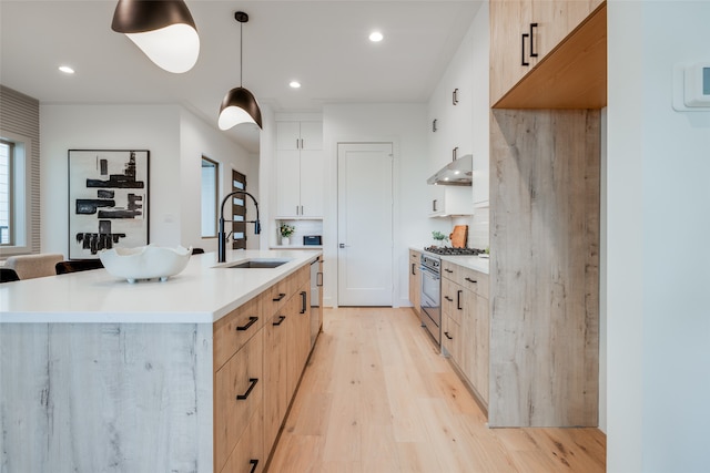 kitchen featuring a sink, light countertops, under cabinet range hood, modern cabinets, and light wood-type flooring