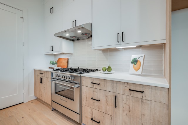 kitchen with tasteful backsplash, light brown cabinetry, white cabinets, high end stainless steel range, and light wood-type flooring