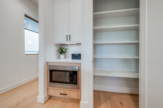 interior space with wood-type flooring, tasteful backsplash, and stainless steel microwave