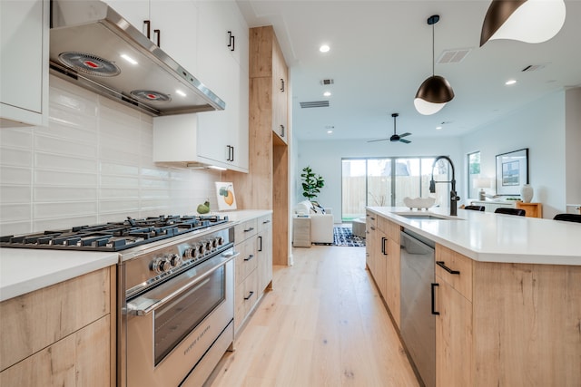 kitchen featuring sink, light wood-type flooring, tasteful backsplash, decorative light fixtures, and stainless steel appliances