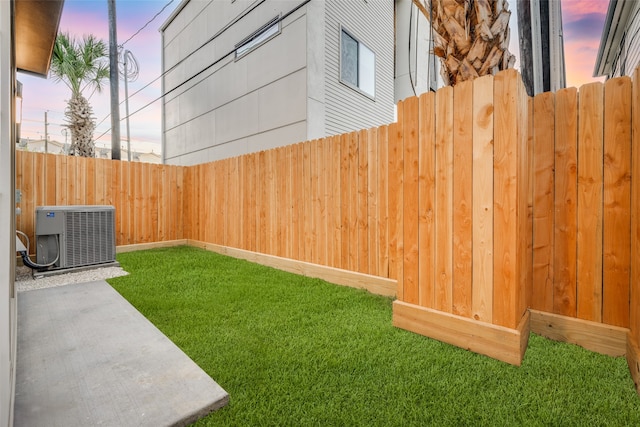 yard at dusk featuring a patio, central air condition unit, and fence