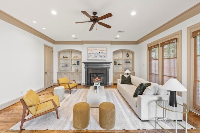 living room with built in features, light wood-type flooring, and ornamental molding