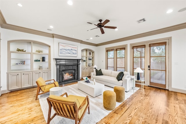 living room featuring a high end fireplace, light hardwood / wood-style floors, ceiling fan, and ornamental molding