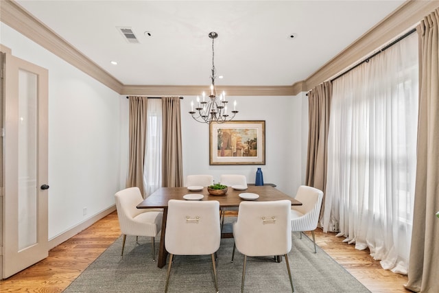 dining space featuring ornamental molding, light hardwood / wood-style floors, and a notable chandelier