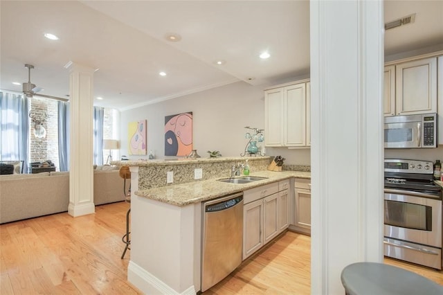 kitchen featuring appliances with stainless steel finishes, kitchen peninsula, sink, and a breakfast bar area