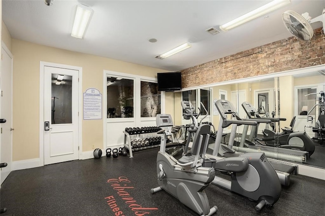 exercise room featuring brick wall