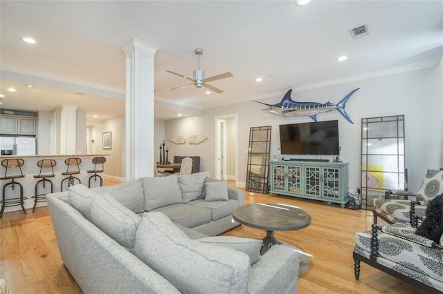 living room featuring ornate columns, ornamental molding, and light wood-type flooring