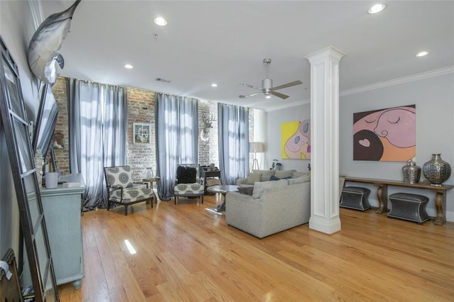 living room with hardwood / wood-style floors, crown molding, ceiling fan, and ornate columns