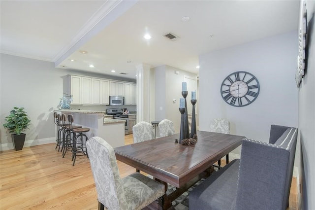 dining room with crown molding and light hardwood / wood-style floors