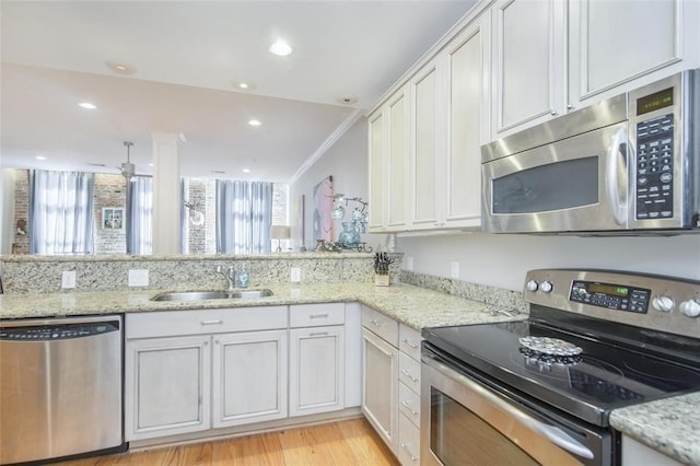 kitchen with stainless steel appliances, sink, white cabinets, and kitchen peninsula