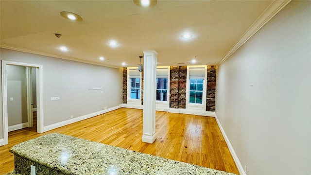 interior space featuring crown molding, decorative columns, and light wood-type flooring