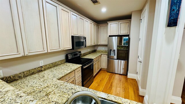 kitchen featuring stainless steel appliances, light stone countertops, and light hardwood / wood-style flooring