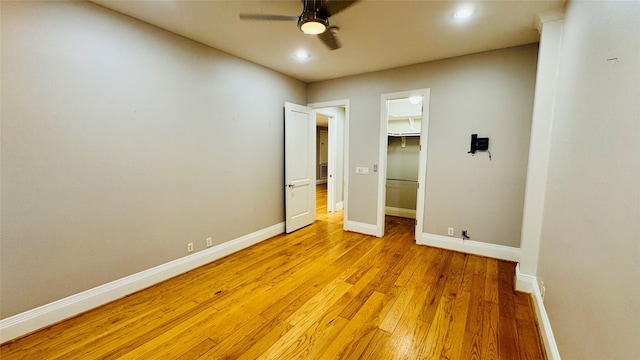 unfurnished bedroom with a spacious closet, light hardwood / wood-style flooring, a closet, and ceiling fan