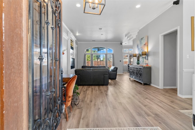 foyer entrance with a chandelier, light wood-type flooring, and ornamental molding