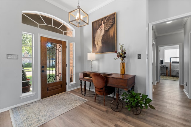 foyer entrance featuring light wood-type flooring, crown molding, and an inviting chandelier