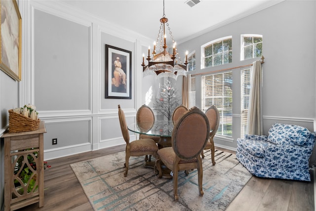 dining room featuring wood-type flooring, ornamental molding, and a chandelier