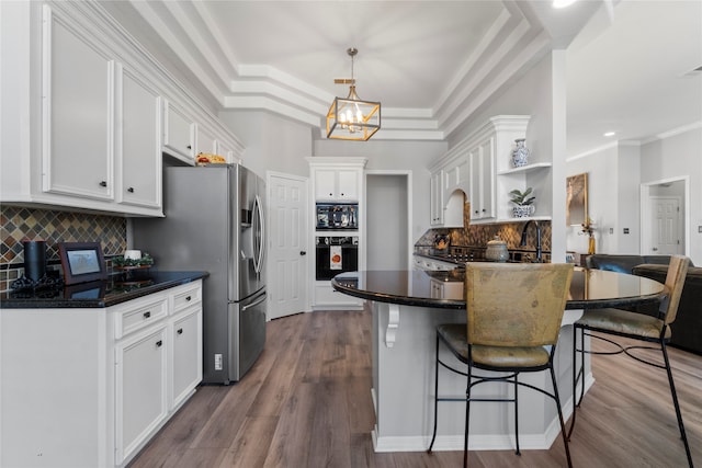 kitchen featuring white cabinets, hardwood / wood-style floors, decorative backsplash, and hanging light fixtures