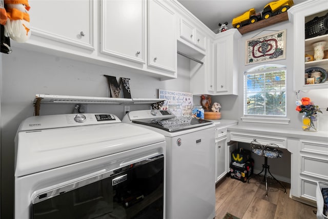 laundry room featuring washer and clothes dryer, cabinets, and light hardwood / wood-style flooring