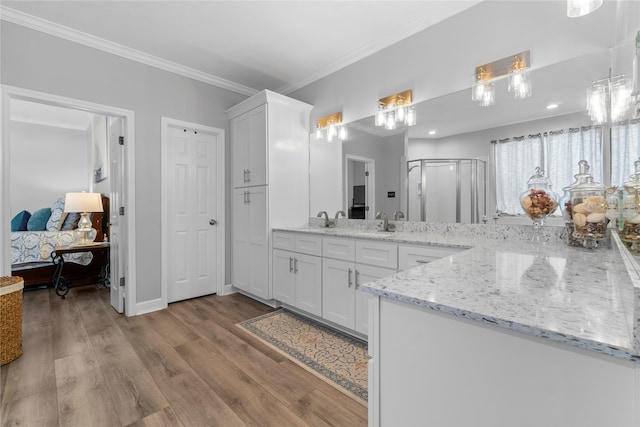 bathroom featuring hardwood / wood-style floors, vanity, a shower with door, and crown molding