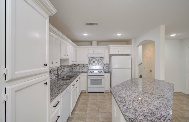 kitchen with white cabinets, light stone countertops, white appliances, and sink