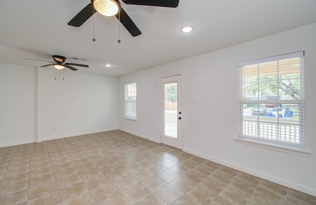 tiled empty room with ceiling fan and a healthy amount of sunlight