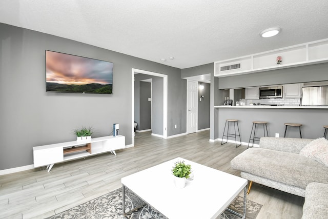 living room featuring a textured ceiling and light wood-type flooring