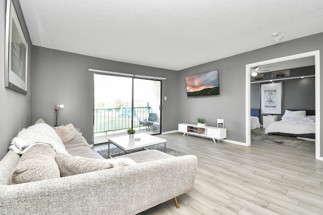 living room with hardwood / wood-style floors, ceiling fan, and a textured ceiling