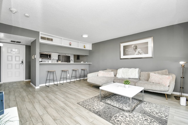 living room with light hardwood / wood-style floors and a textured ceiling