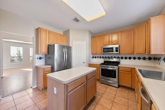 kitchen with sink, light tile patterned flooring, a center island, and appliances with stainless steel finishes