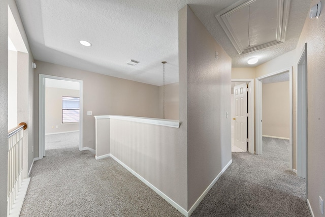 hall with light colored carpet and a textured ceiling