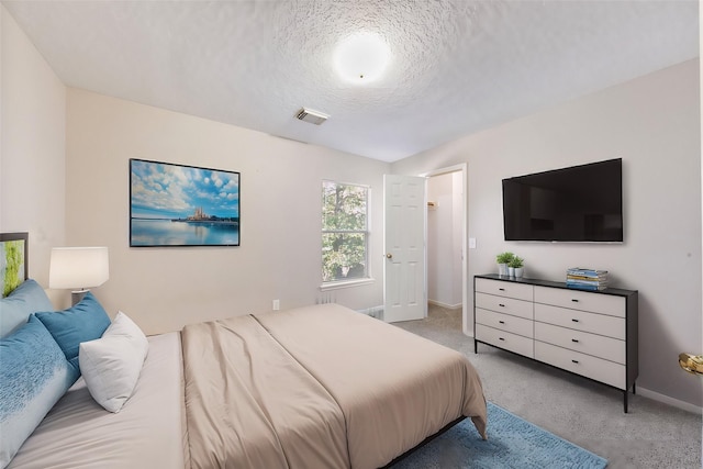 bedroom with light colored carpet and a textured ceiling