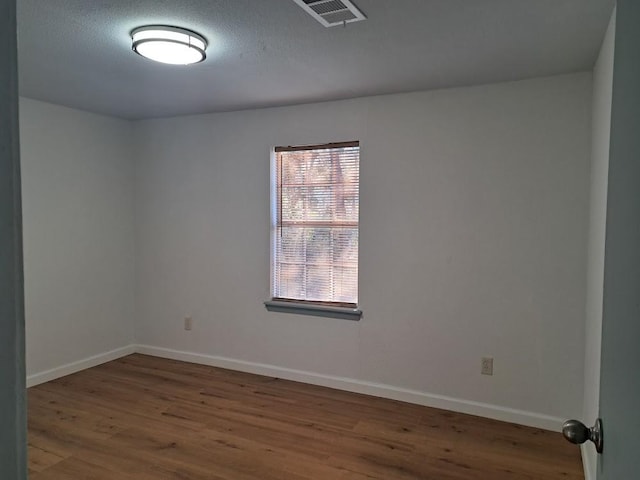 spare room with a textured ceiling and dark hardwood / wood-style floors