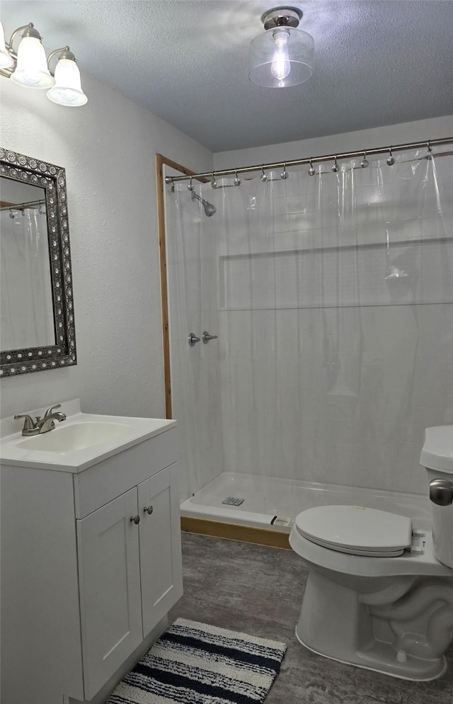 bathroom featuring a shower with shower curtain, vanity, a textured ceiling, and toilet