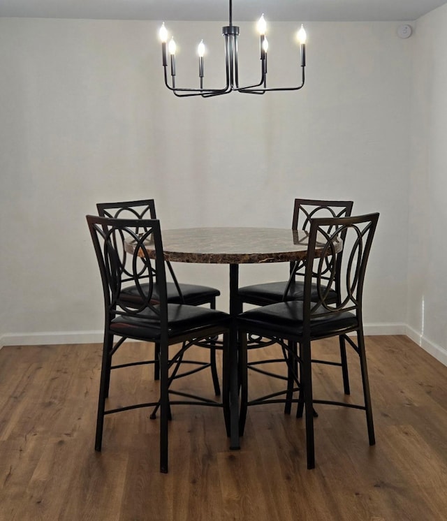 dining area with dark wood-type flooring and a notable chandelier