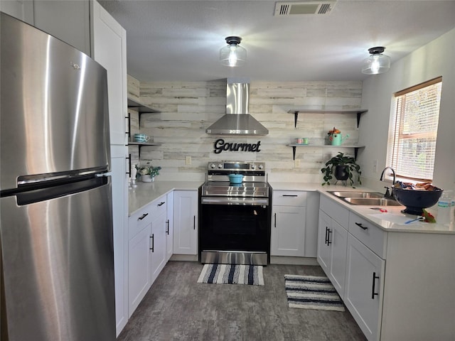 kitchen featuring wall chimney exhaust hood, sink, wooden walls, stainless steel appliances, and white cabinets