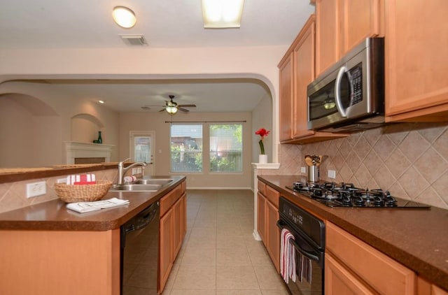 kitchen with sink, backsplash, a kitchen island with sink, light tile patterned floors, and black appliances