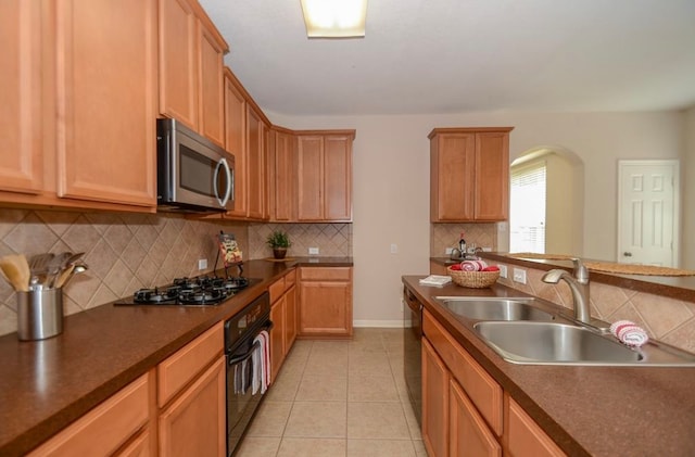 kitchen featuring sink, light tile patterned floors, backsplash, and black appliances