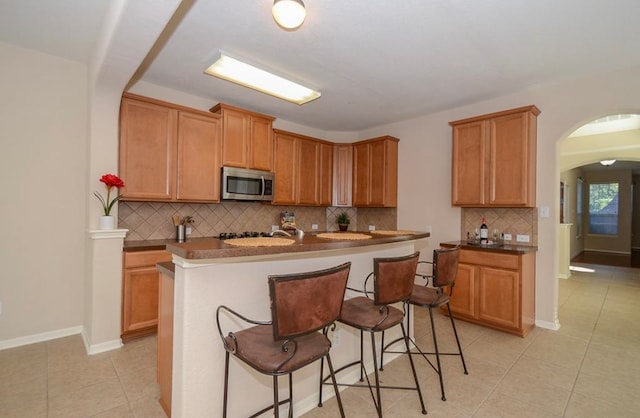 kitchen with a kitchen bar, a kitchen island with sink, and tasteful backsplash