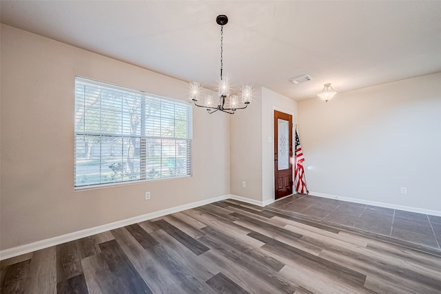 empty room with dark hardwood / wood-style floors and an inviting chandelier