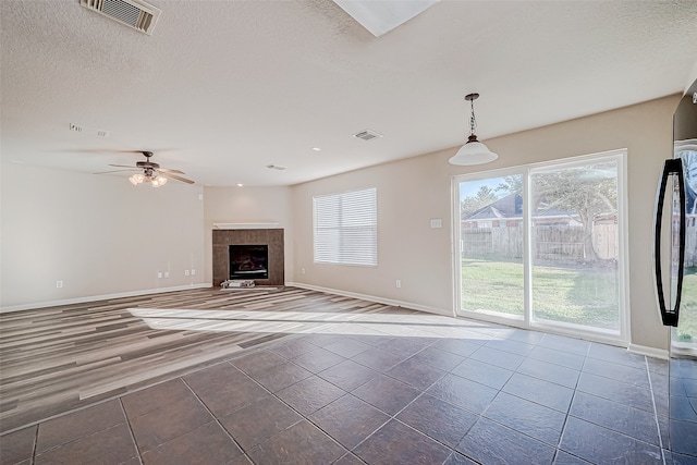 unfurnished living room featuring tile patterned floors, ceiling fan, a textured ceiling, and a tile fireplace