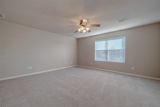 empty room featuring light carpet, ceiling fan, and a textured ceiling