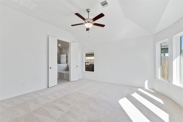 unfurnished bedroom featuring connected bathroom, multiple windows, lofted ceiling, and ceiling fan