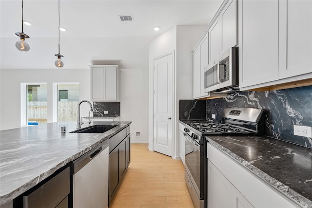 kitchen featuring backsplash, stainless steel appliances, sink, decorative light fixtures, and light hardwood / wood-style floors