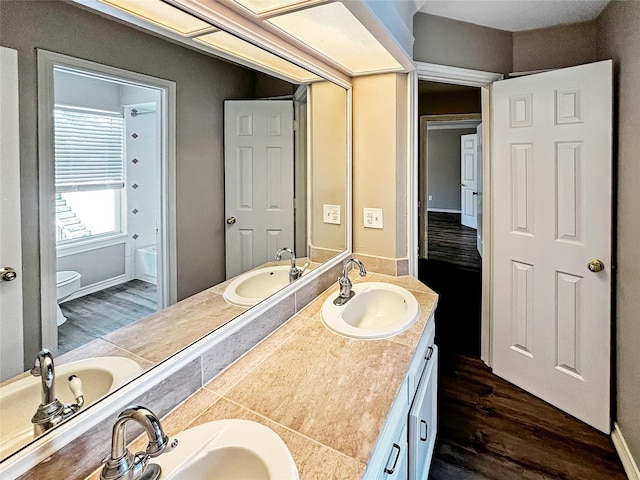 1519 Hannington Dr, Katy, TX 77450 - bathroom featuring wood finished floors, double vanity, toilet, and baseboards