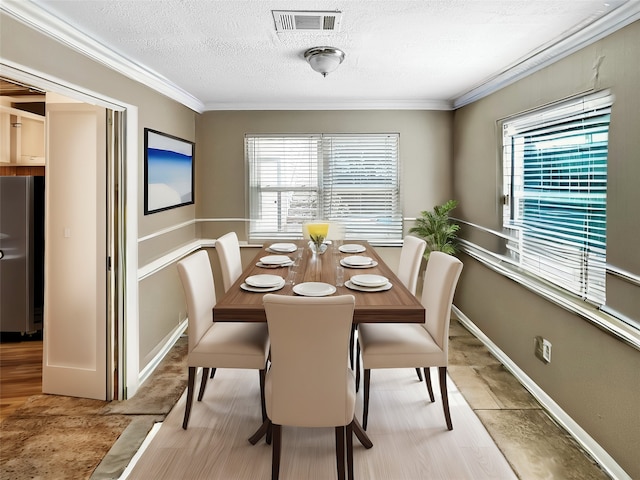 dining room with ornamental molding, a textured ceiling, light hardwood / wood-style floors, and a healthy amount of sunlight